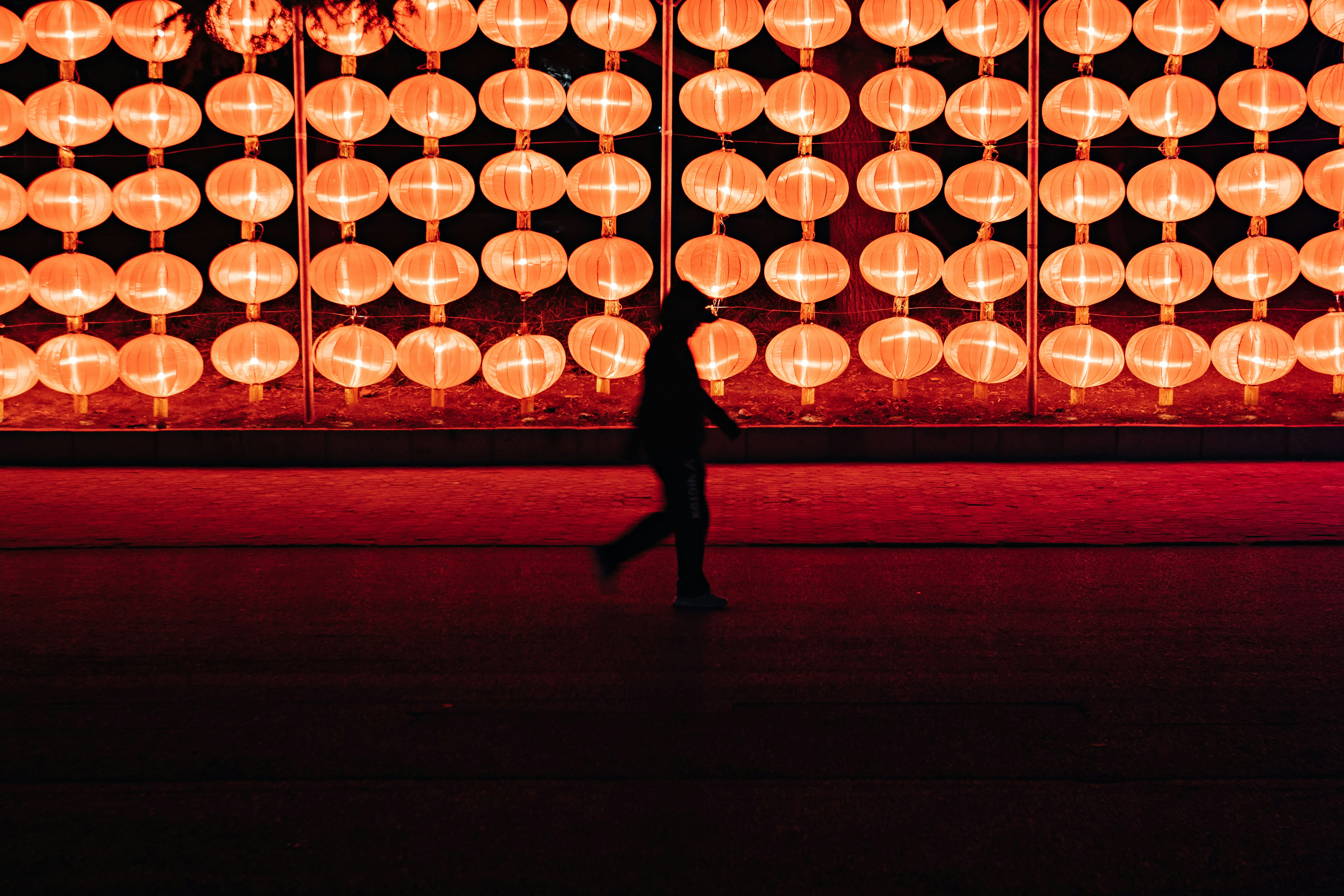 silhouette of person walking near lantern lamp